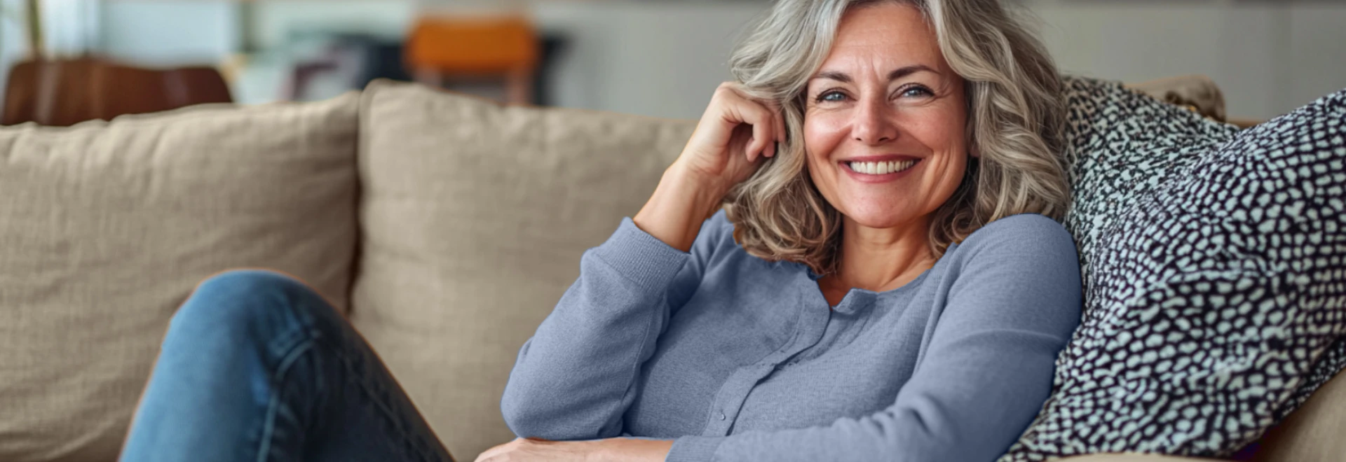 Eine Frau auf der Couch lächelt in die Kamera