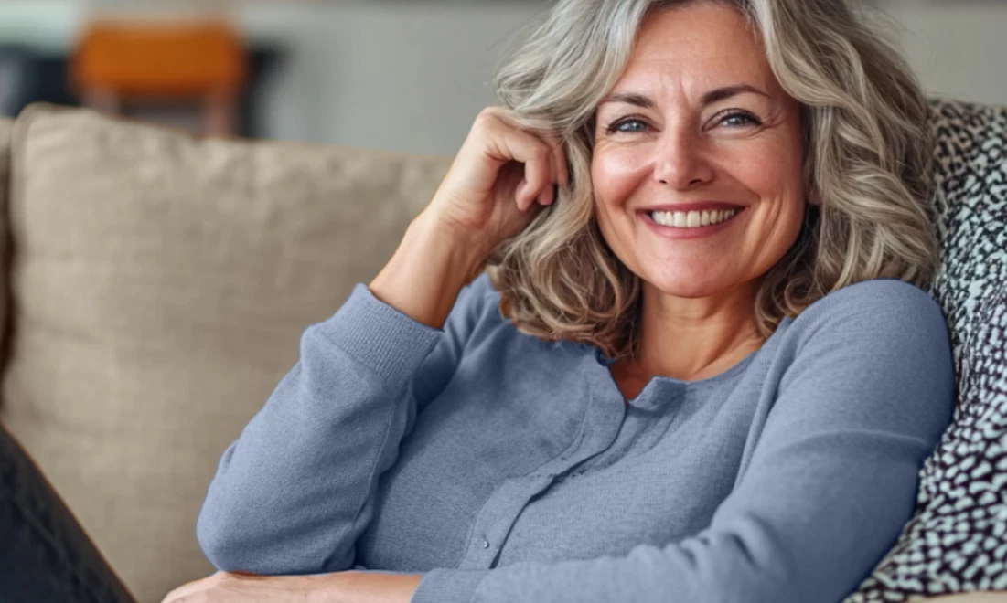 Eine Frau auf der Couch lächelt in die Kamera